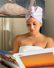 Woman wearing a mermaid pattern multicolor microfiber turbie twist hair towel, reading a book in bed